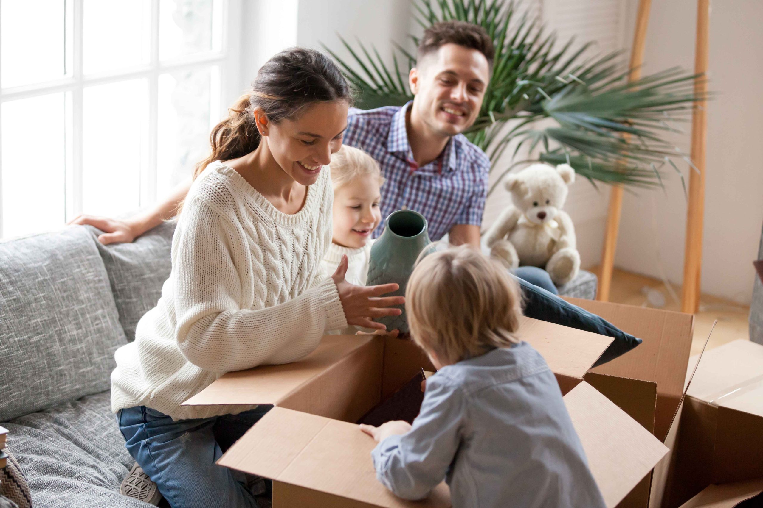 happy family with kids unpacking boxes moving into new home
